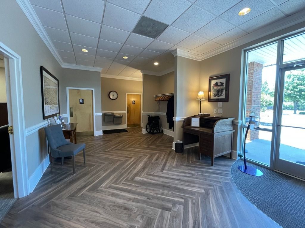 Lobby with wood-look floors, desk, seating, and a large glass door. Neutral colors.