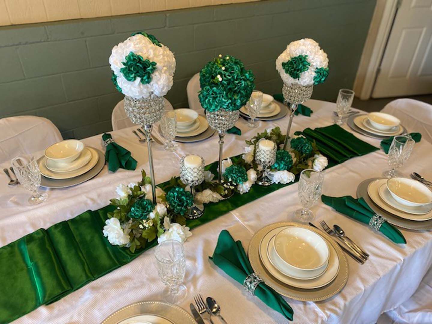 Table setting with green and white floral centerpieces, formal place settings.