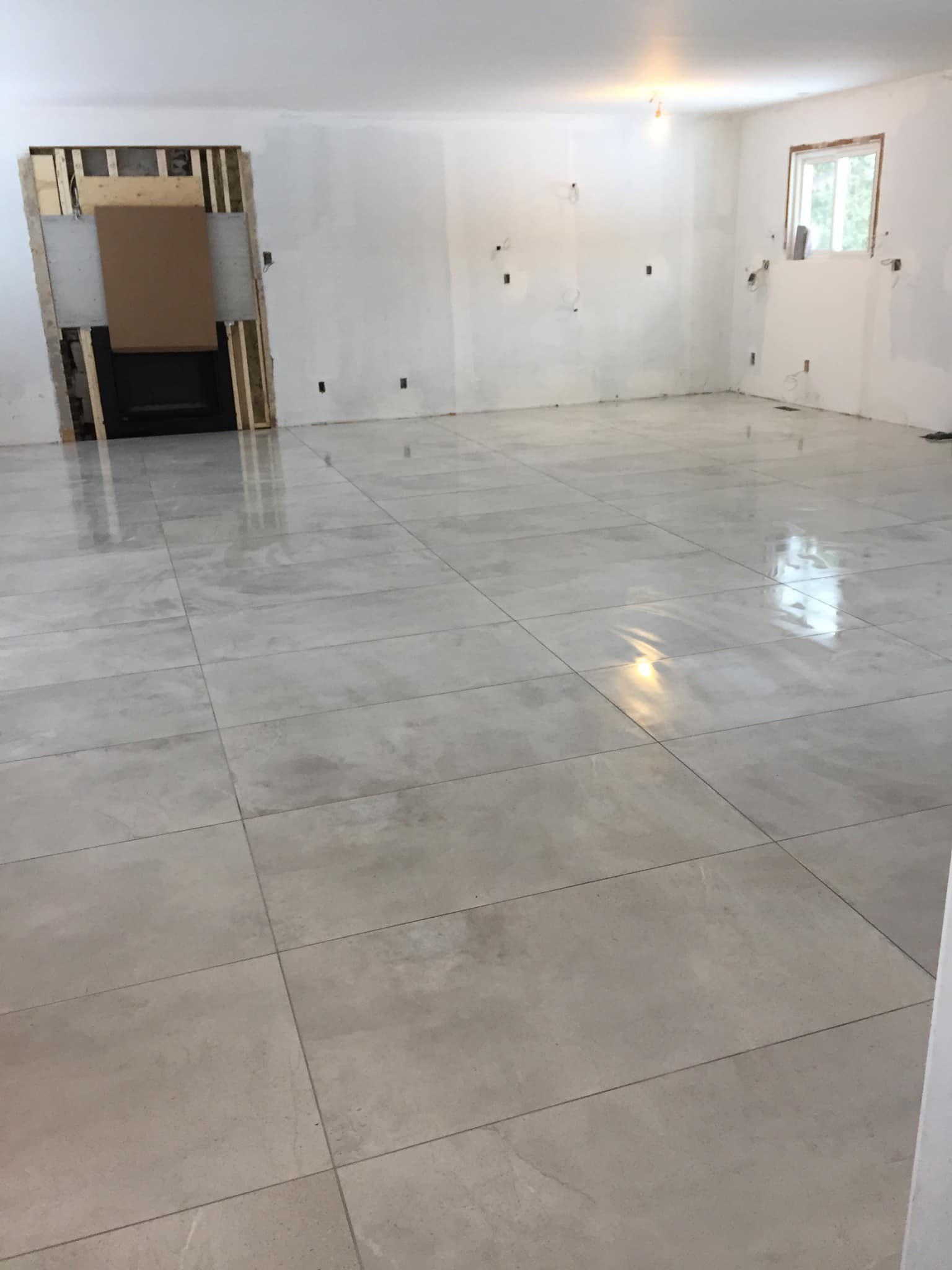 Empty white room with glossy tiled floor, doorway on the left, and a small window on the right.