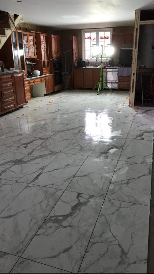 Empty living room with glossy white marble tile floor, dark wood cabinets, and a window at the back.