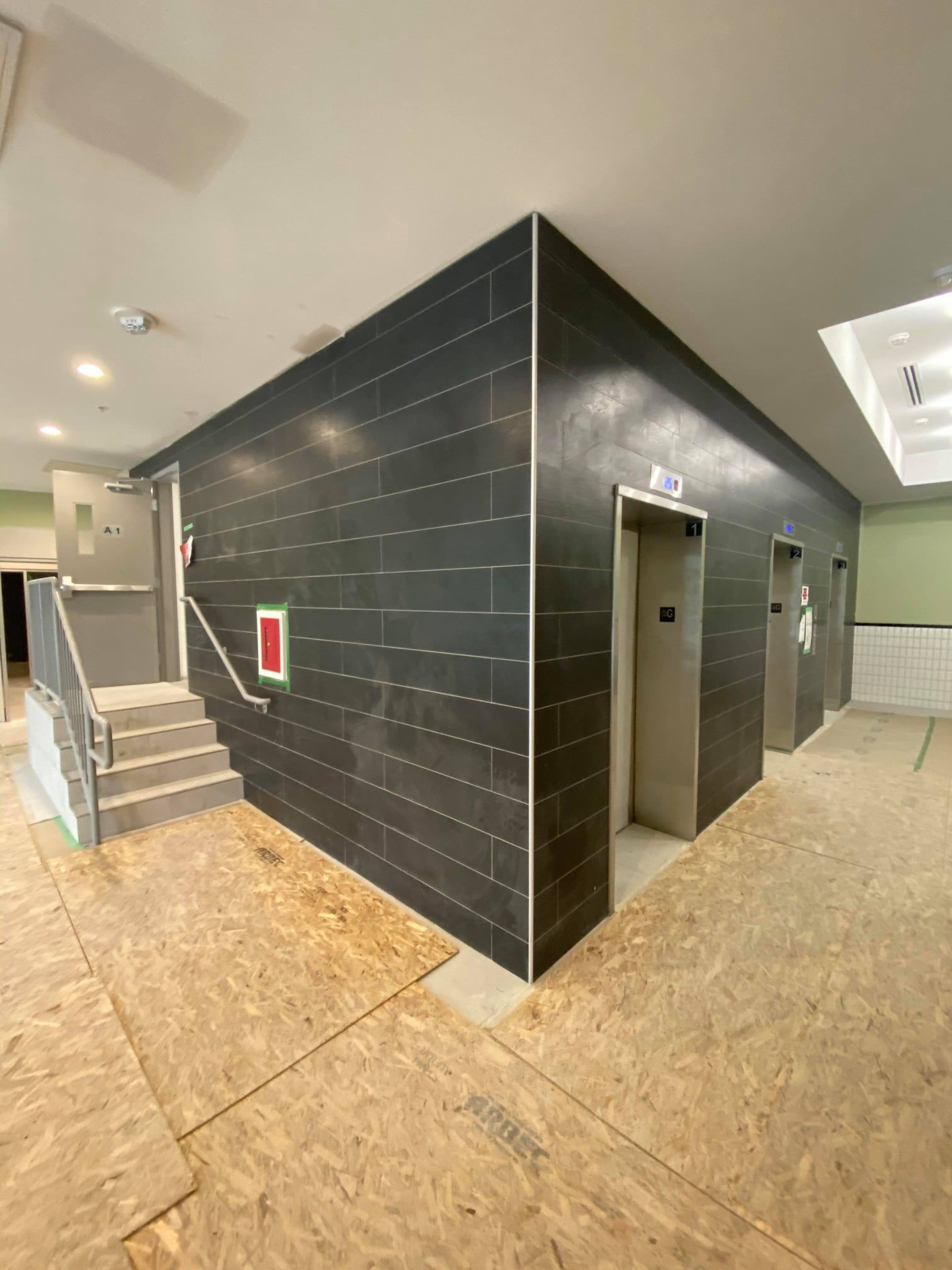 Modern building hallway with black tiled elevator shaft and stairs in a construction area