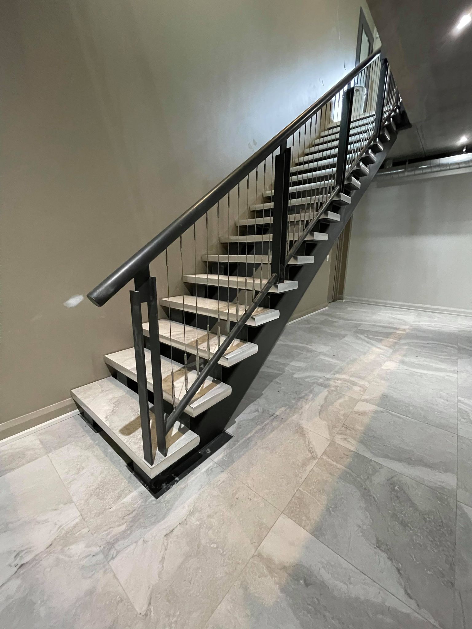 Black metal staircase with wooden steps in a modern indoor hallway