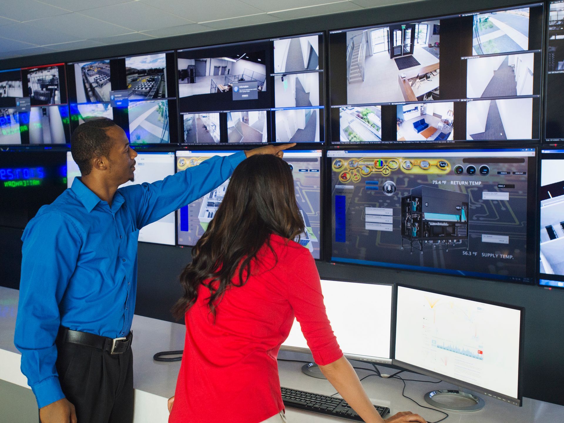 A man and woman in front of a large monitor, exploring options for network video recording. 