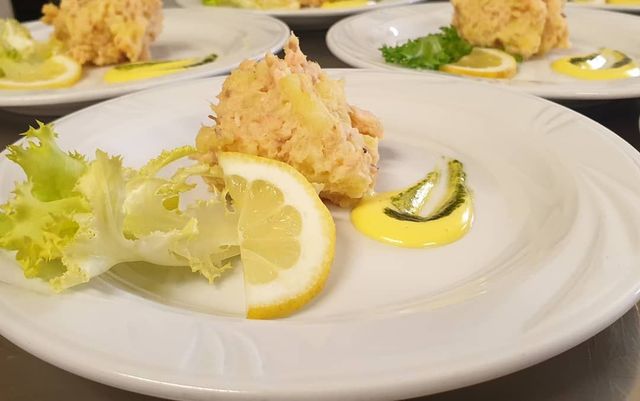 Insalata di frutti di mare servita su piatti bianchi con spicchi di limone e guarnizione di lattuga.