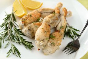 Pollo grigliato con spicchi di limone e rosmarino su un piatto bianco