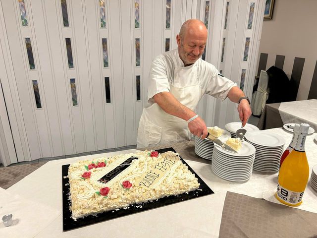 Un uomo serve una torta a un tavolo da banchetto con un grande dessert decorato e piatti impilati.