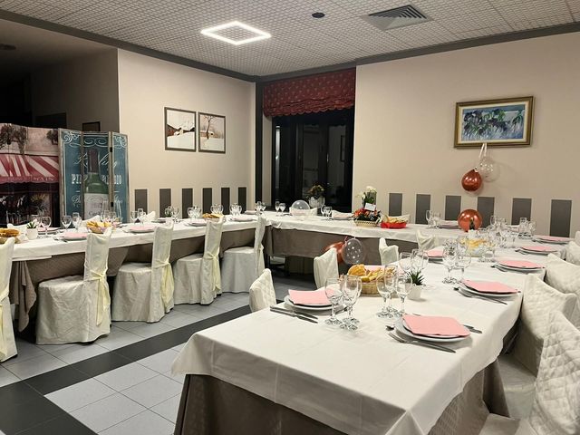 Sala per banchetti con tavoli apparecchiati, coprisedie bianchi e tovaglioli rosa in un ambiente simile a quello di un hotel.