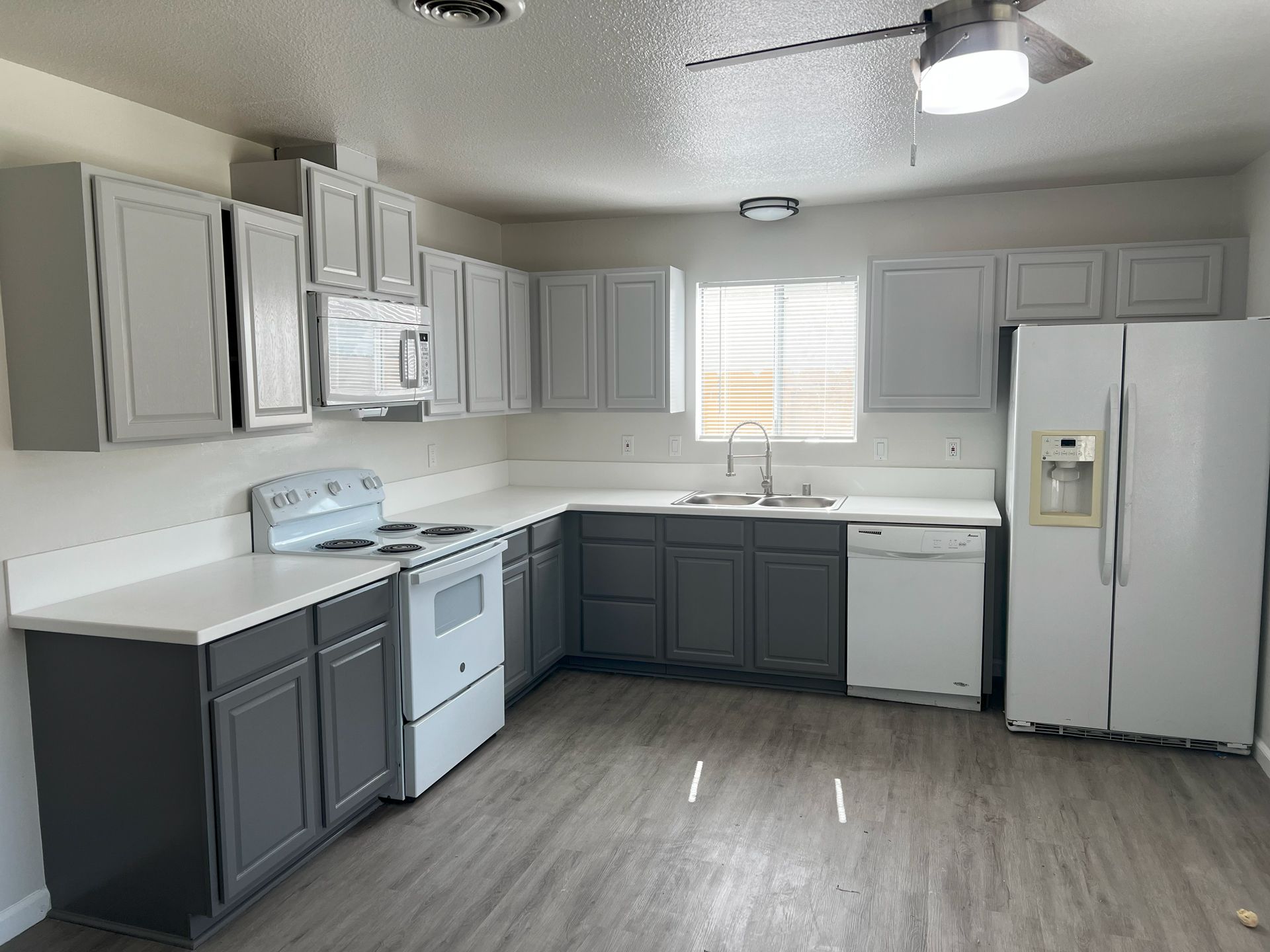 A kitchen with gray cabinets , white appliances , and a refrigerator.