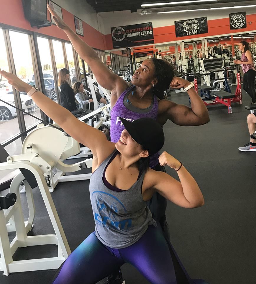 Two women are posing for a picture in a gym