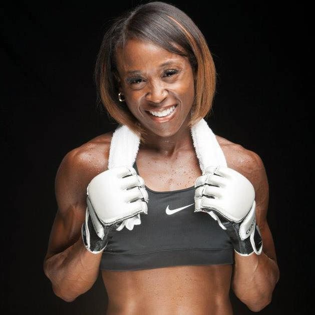 A woman wearing boxing gloves and a towel around her neck
