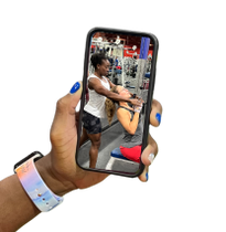 A person is holding a cell phone with a picture of a man and a woman in a gym.