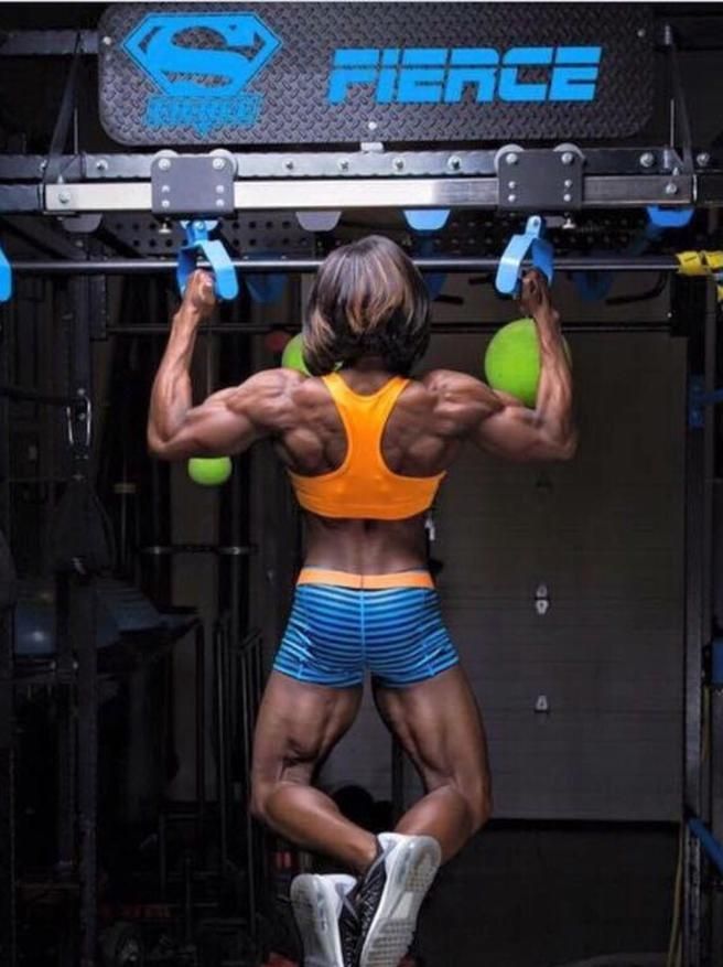 A woman is doing pull ups in front of a sign that says fierce
