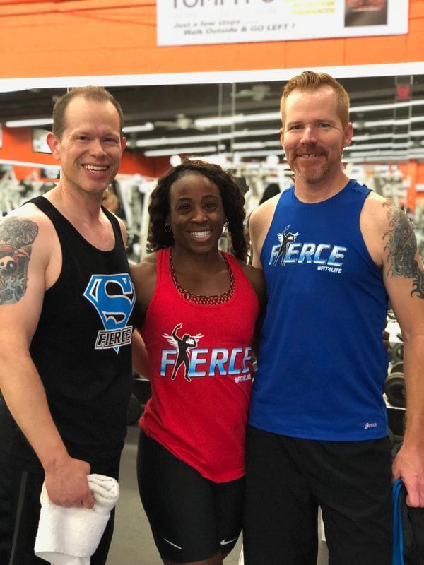 Three people posing for a picture in a gym wearing shirts that say fierce