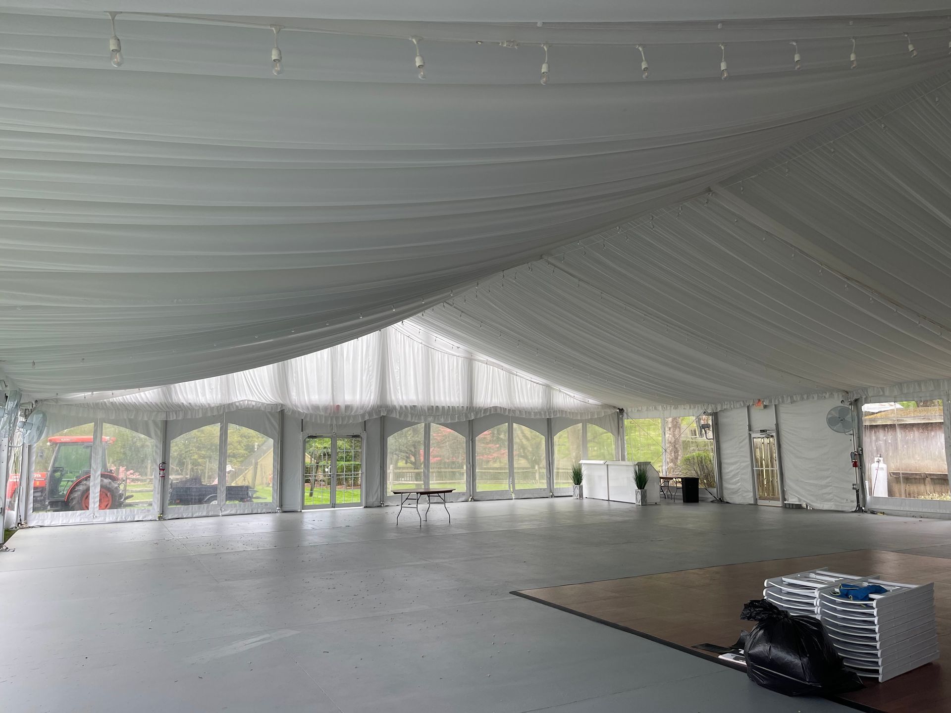 Interior view of a large white tent with arched windows and a gray floor.