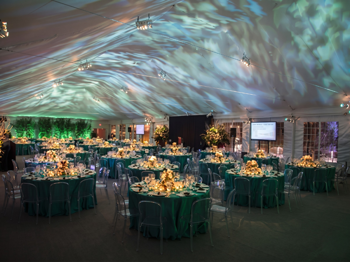 Elegant banquet hall with round tables, green chairs, and blue-green light patterns on the ceiling