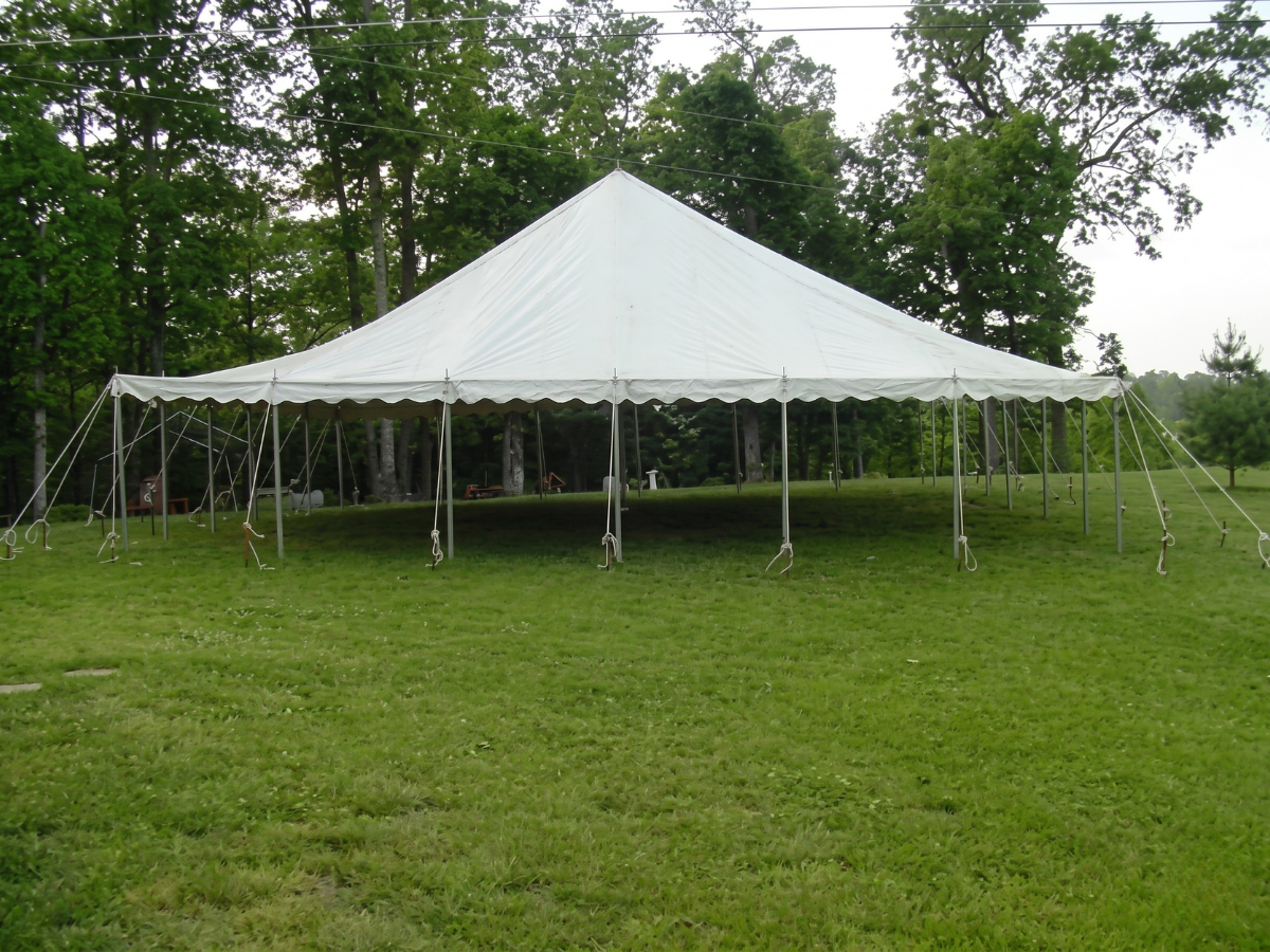 Large white event tent on a grassy field with trees in the background