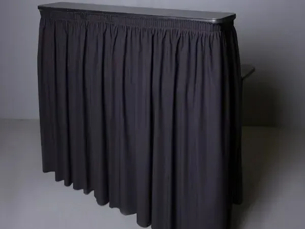 Dark pleated curtain covering a rectangular table or display stand