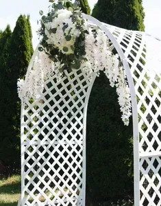 White lattice wedding arch with cascading white flowers and greenery outdoors