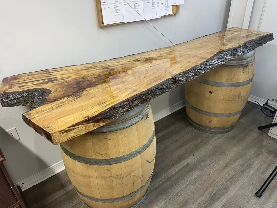 Live-edge wooden tabletop resting on two barrel-style supports in a room