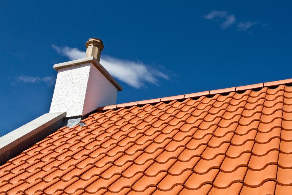 A Chimney on Top of a Tiled Roof With a Blue Sky in the Background — Leonard Gray Roof Tiling In Casino, NSW