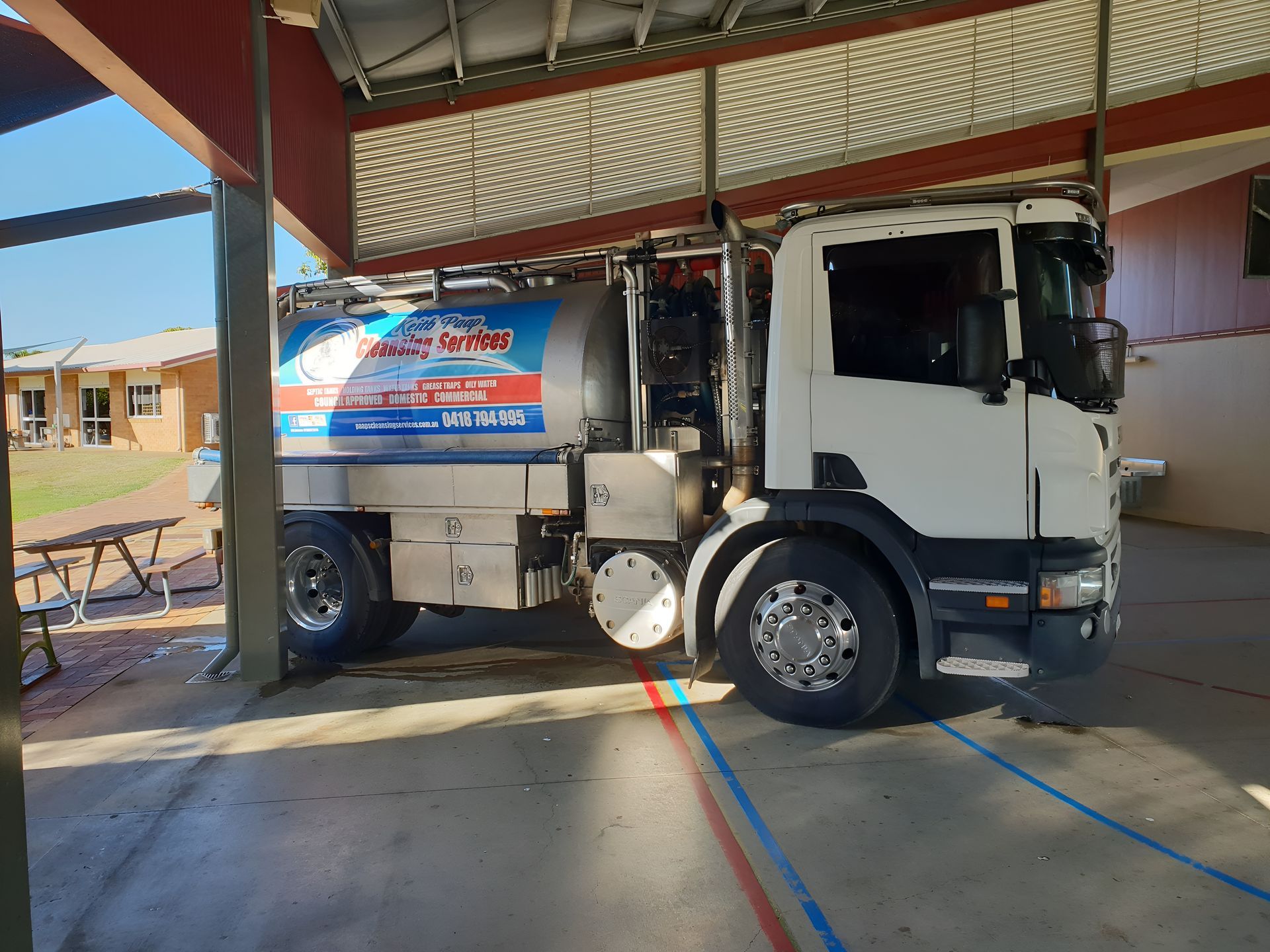 White Tanker Truck Parked Under a Covered Area — Paap's Cleansing Services in Childers, QLD