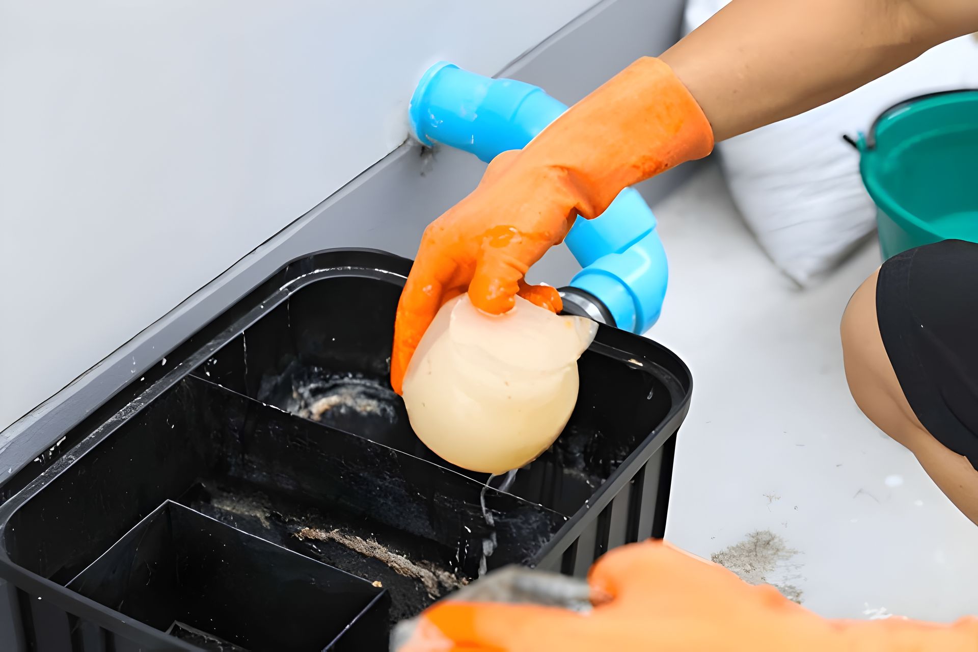Person Wearing Orange Gloves Cleaning a Grease Trap — Paap's Cleansing Services in Bargara, QLD