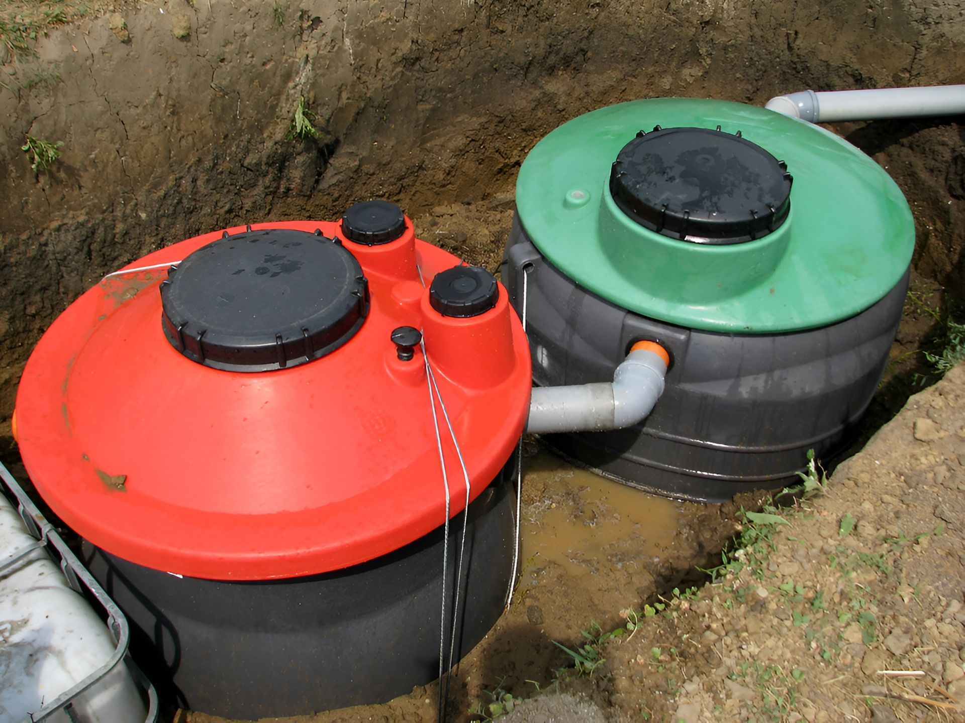 Two Connected Septic Tanks, One Red, One Green, Installed in a Trench — Paap's Cleansing Services in Branyan, QLD
