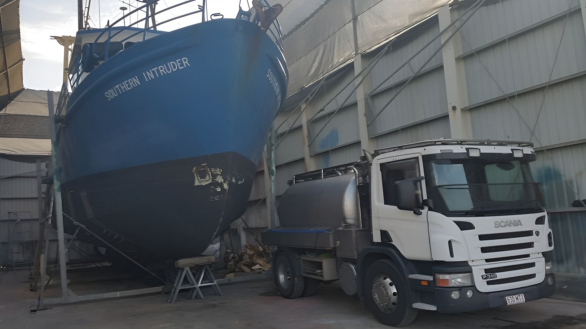 Blue Ship on Supports Next to White Truck in Industrial Setting — Paap's Cleansing Services in Branyan, QLD