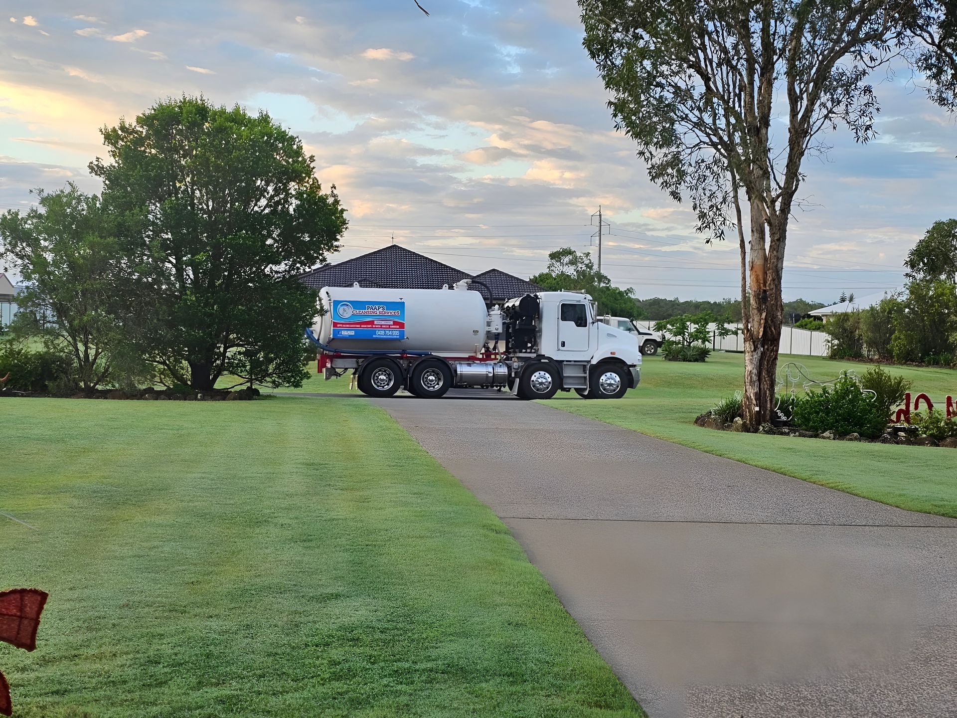 White Tanker Truck Parked on a Driveway in Front of a House — Paap's Cleansing Services in Lowmead, QLD