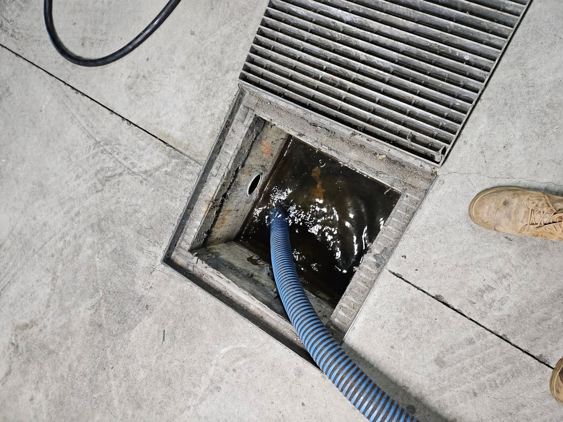 A Drain With a Grate, Concrete Floor and Hose — Paap's Cleansing Services in Gin Gin, QLD