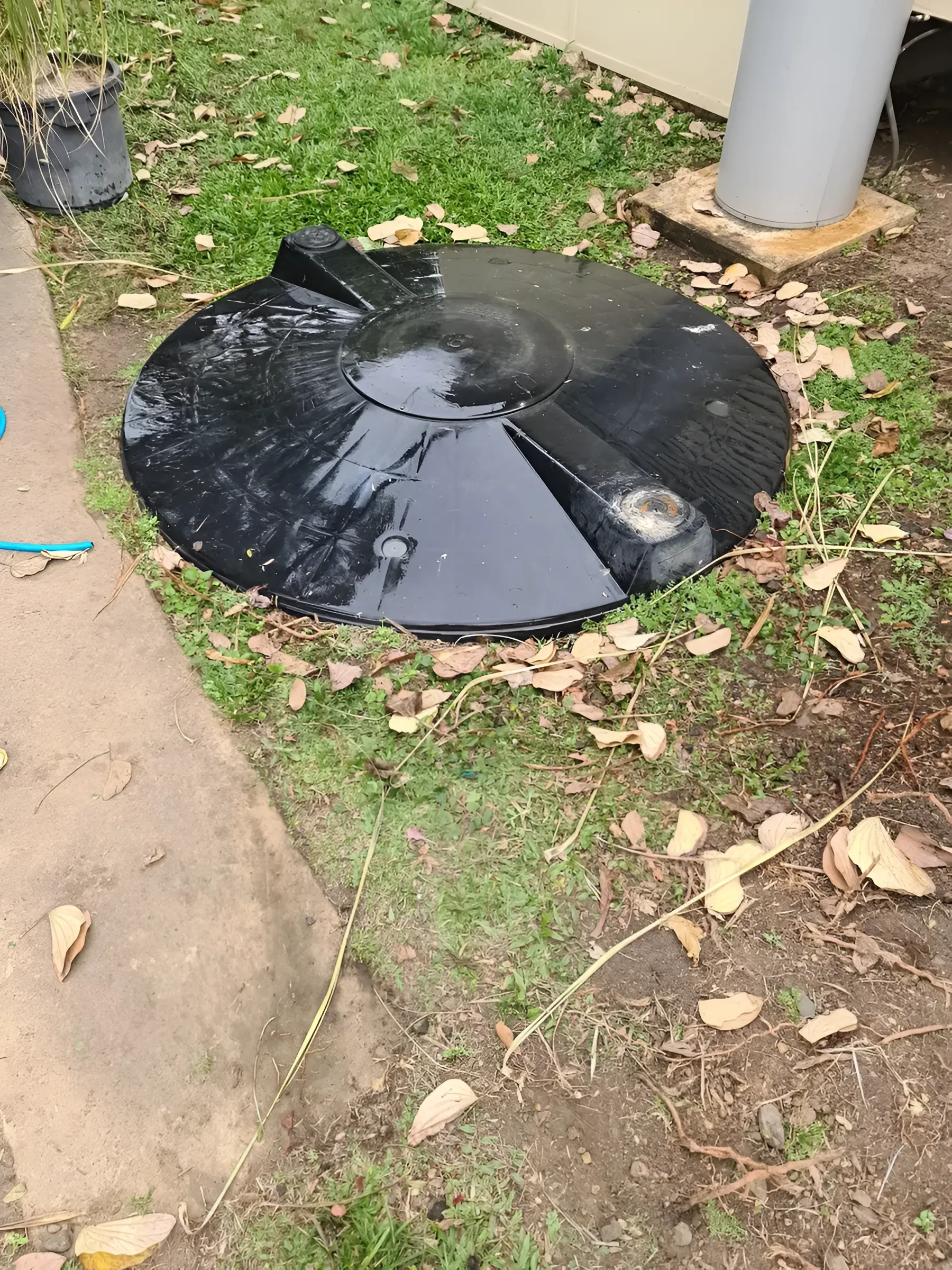 Black Circular Cover on Ground Surrounded by Grass — Paap's Cleansing Services in Branyan, QLD