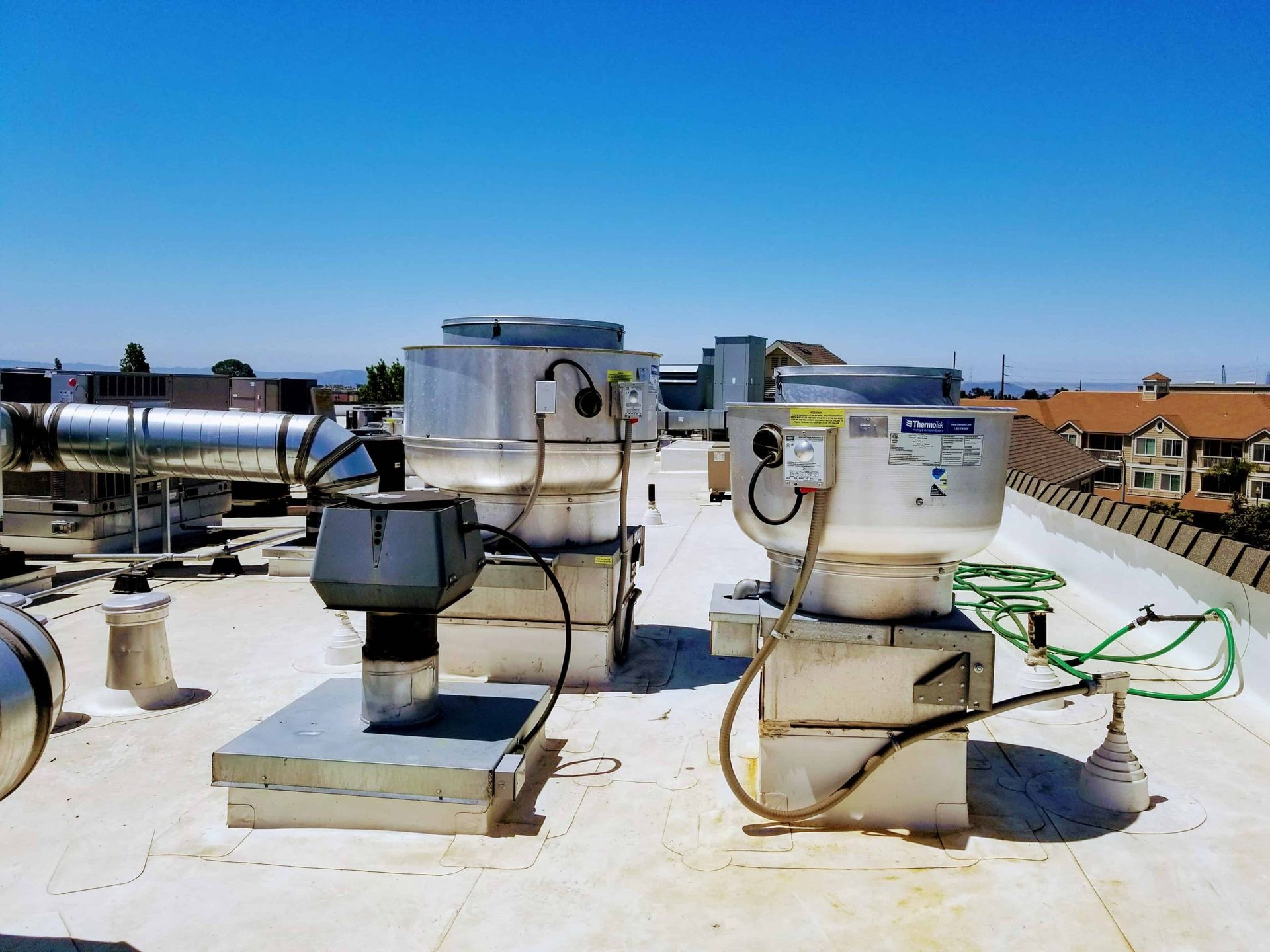 Two exhaust fans are sitting on top of a white roof