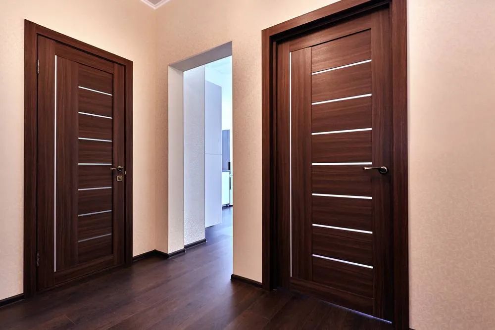 Un corridoio con due porte di legno e un pavimento di legno.