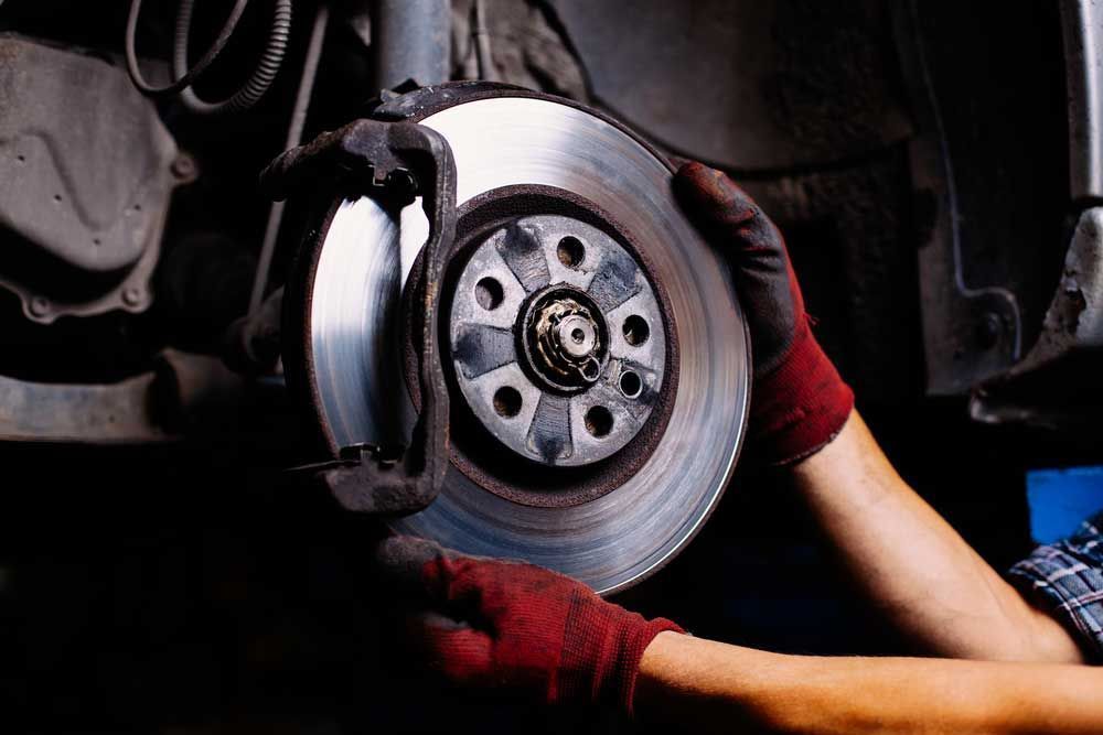 Mechanic Holding a Car Brake Disc — Hervey Bay Brake and Exhaust in Pialba, QLD