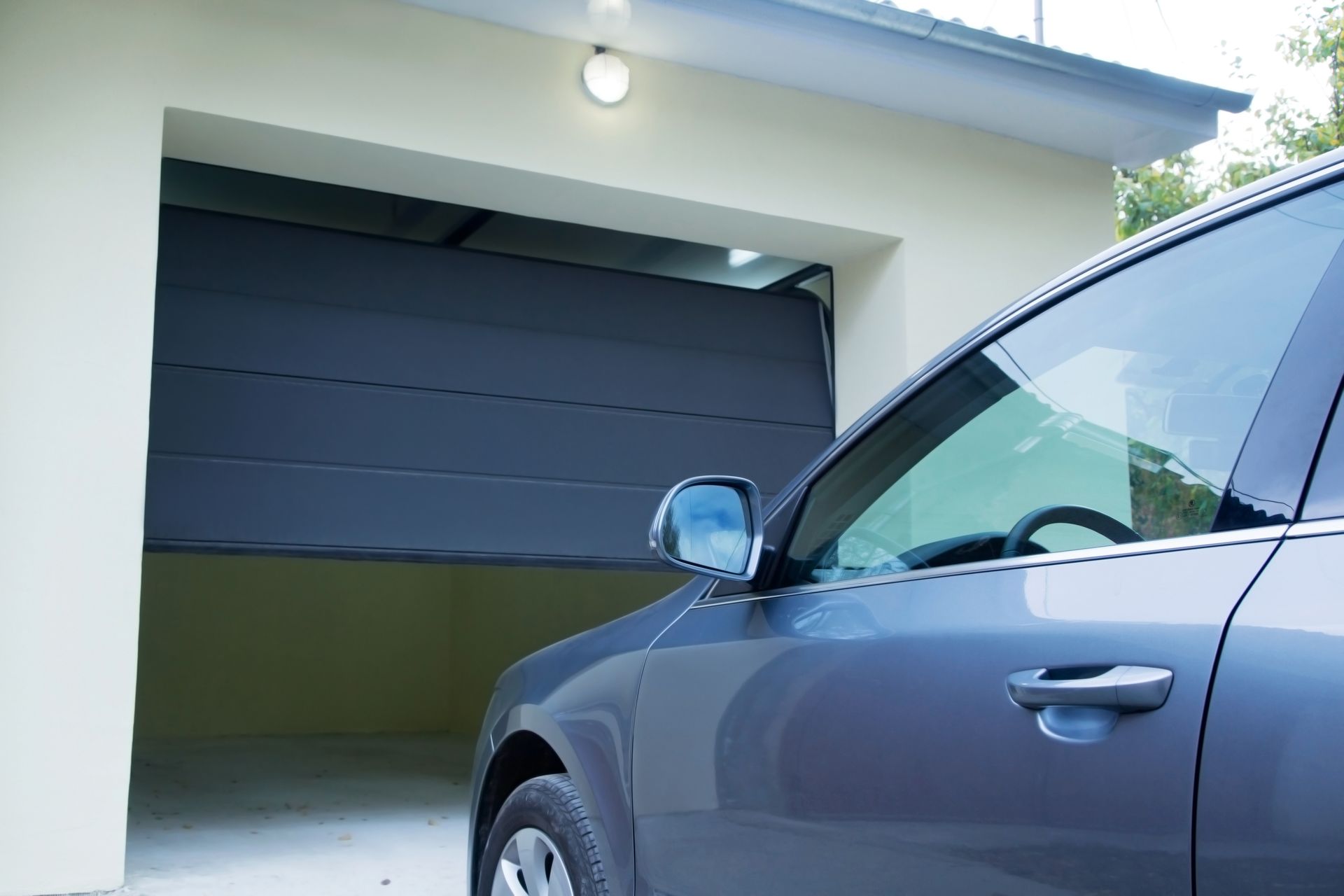 Blue car parked in front of a garage with a closed dark door