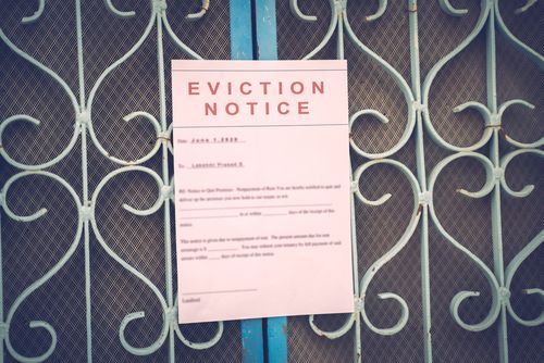 An eviction notice is posted on a decorative metal gate.