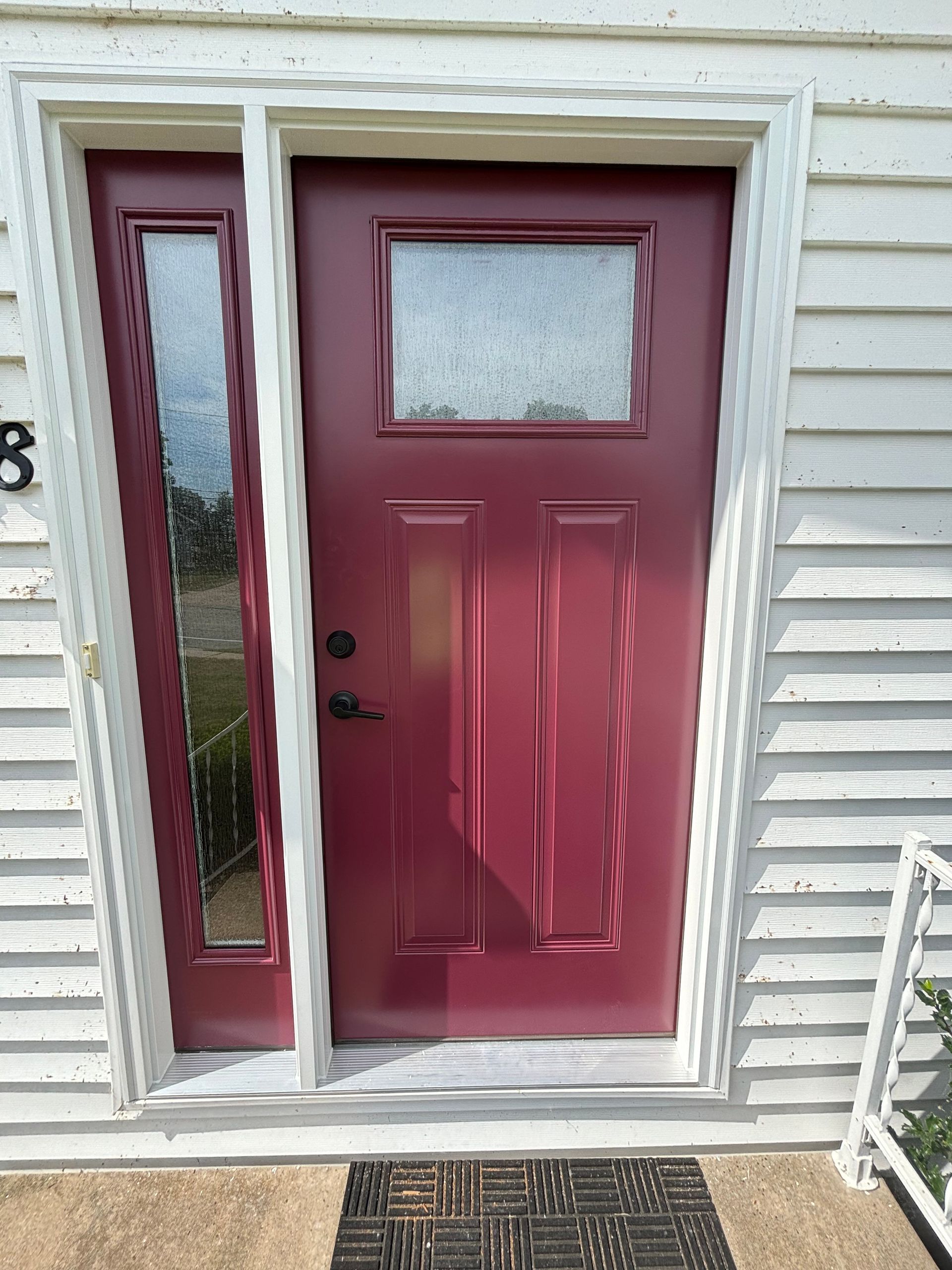 Red front door with narrow sidelight and frosted glass window in white siding