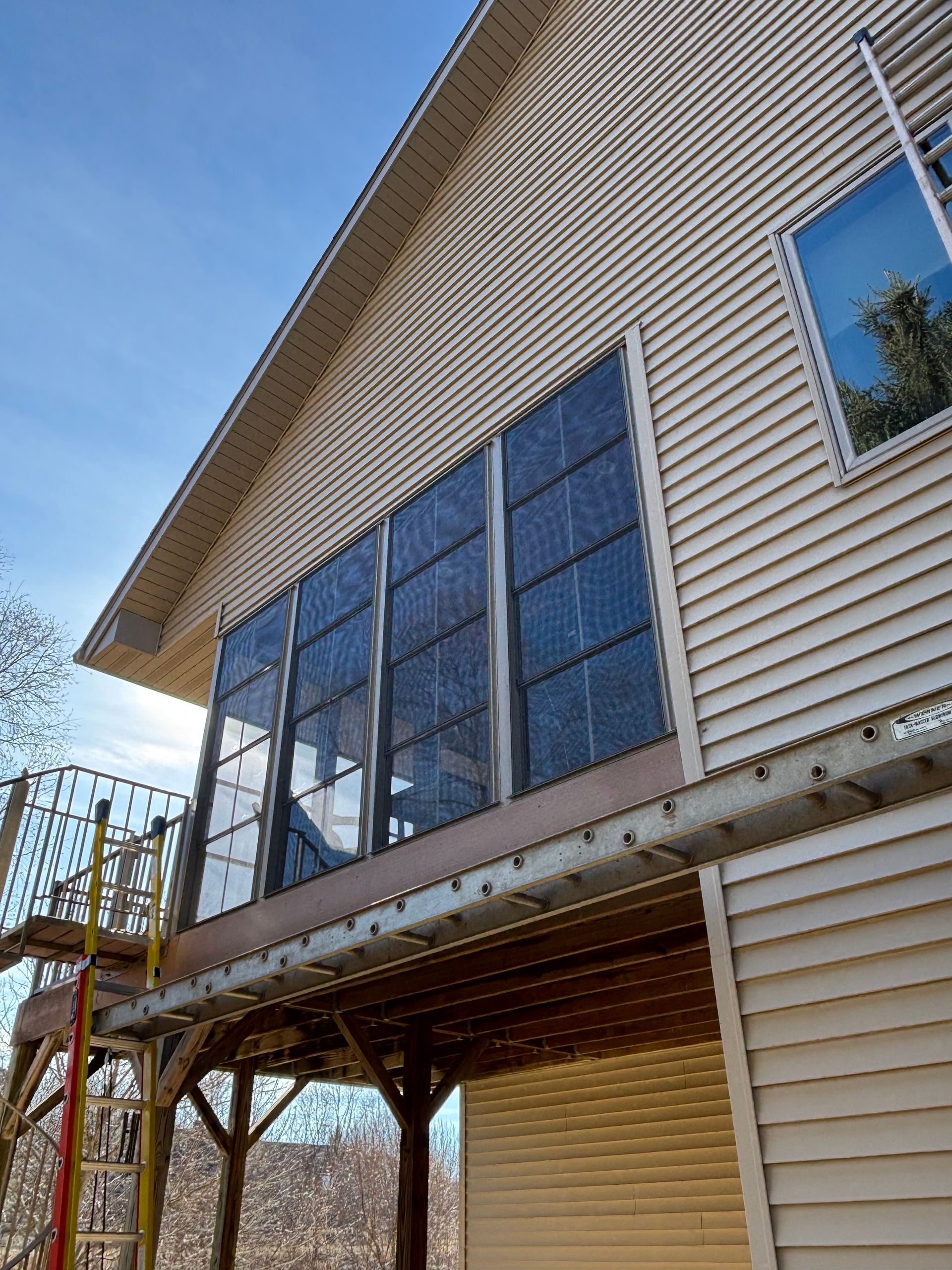 House exterior with large screened porch windows and tan siding beneath a sloped roof