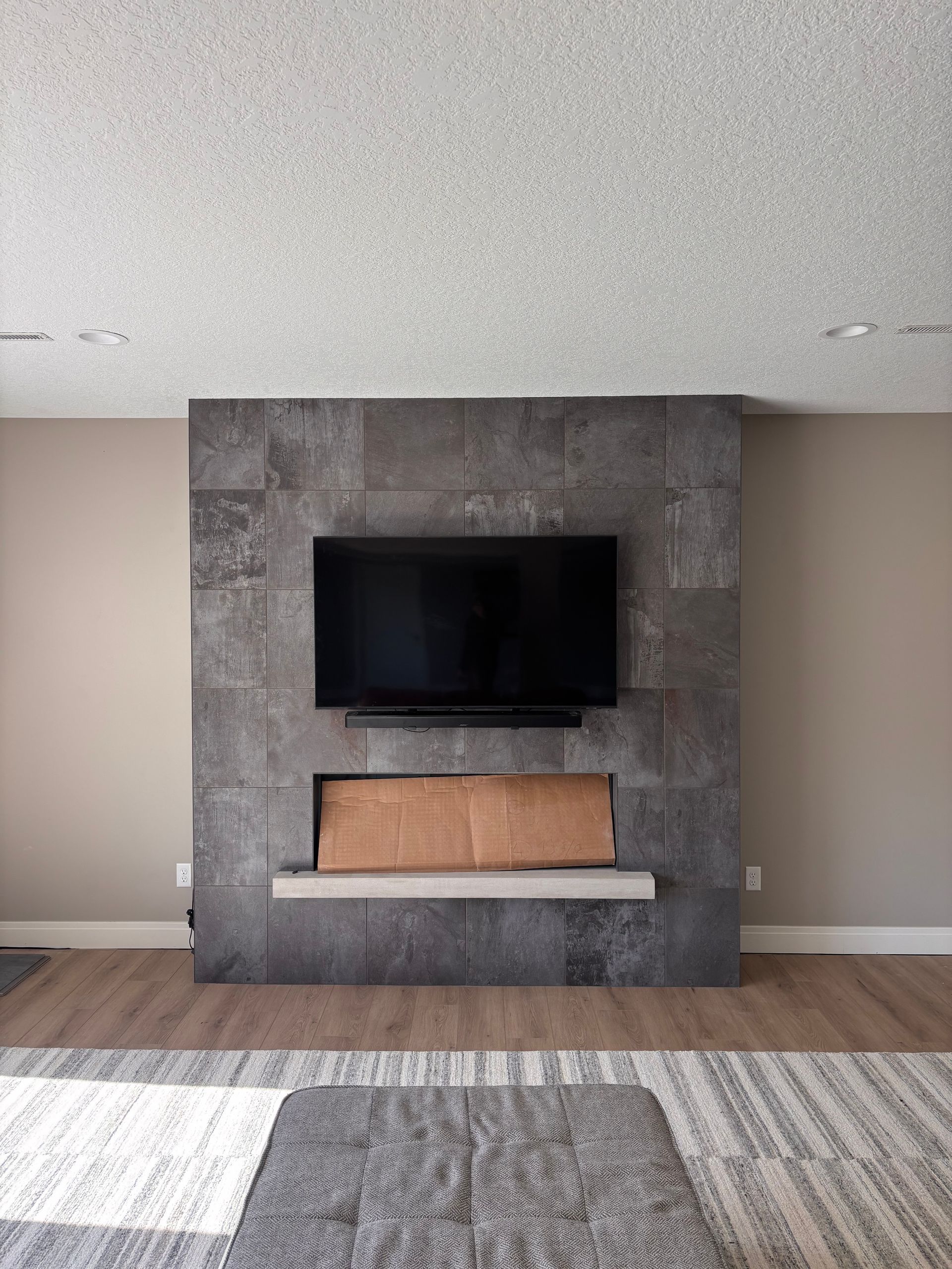 Modern living room with a wall-mounted TV above a fireplace and gray accent wall.