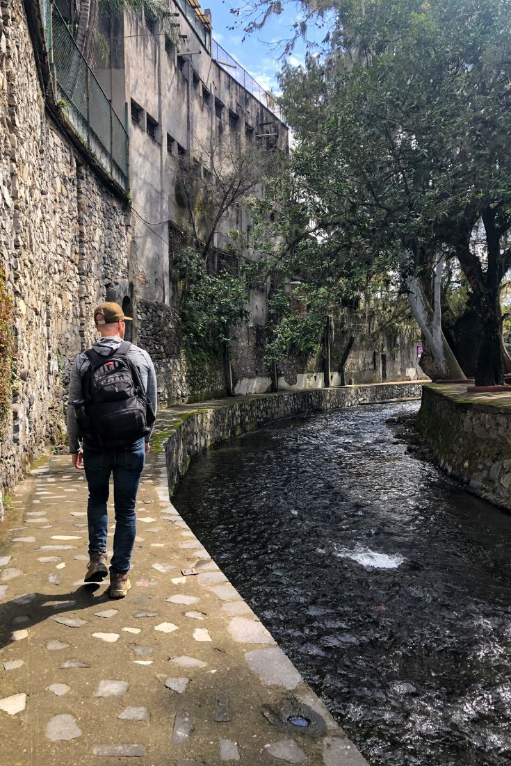 A man is walking down a sidewalk next to a river.