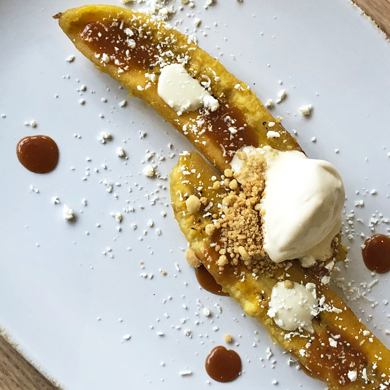 Un plato blanco cubierto con un plátano y helado.
