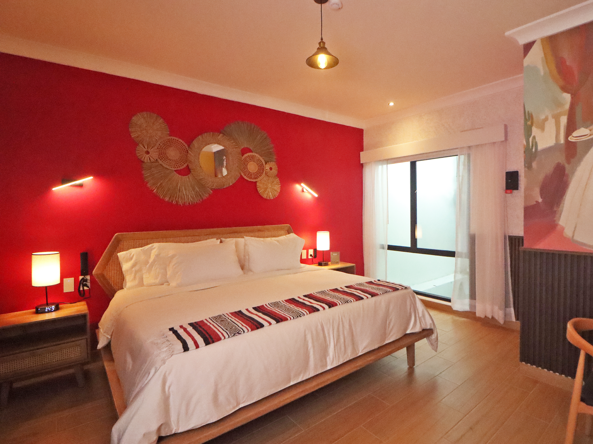 Un dormitorio con una cama y sombreros de paja en la pared.