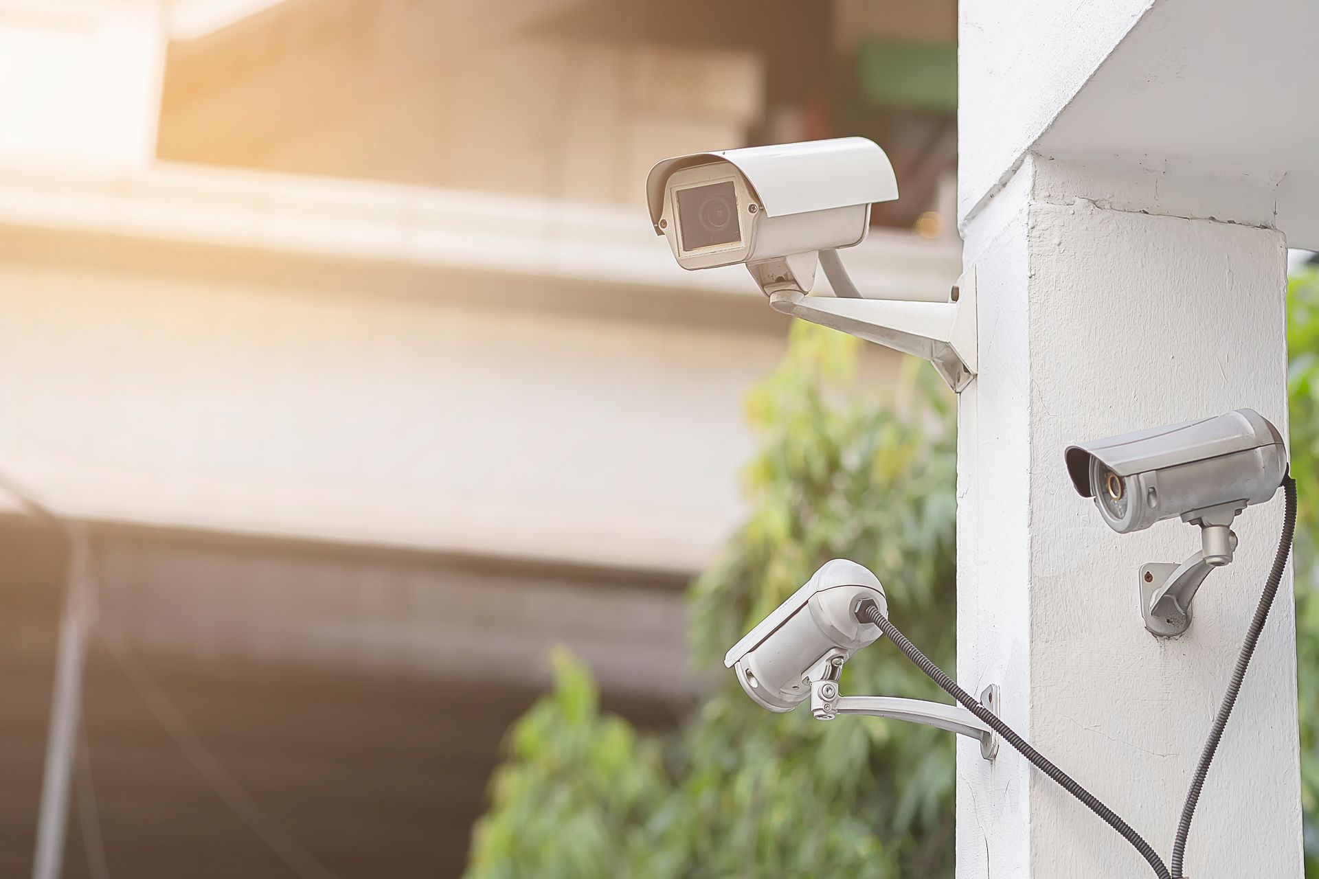 Three security cameras mounted on a white column, angled towards an outdoor area.