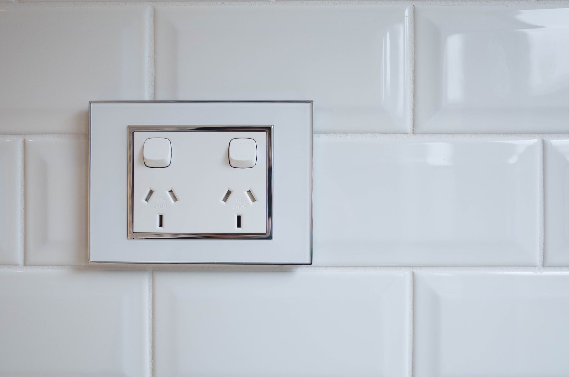 A double Australian power outlet installed on a white tiled wall. A double Australian power outlet installed on a white tiled wall.