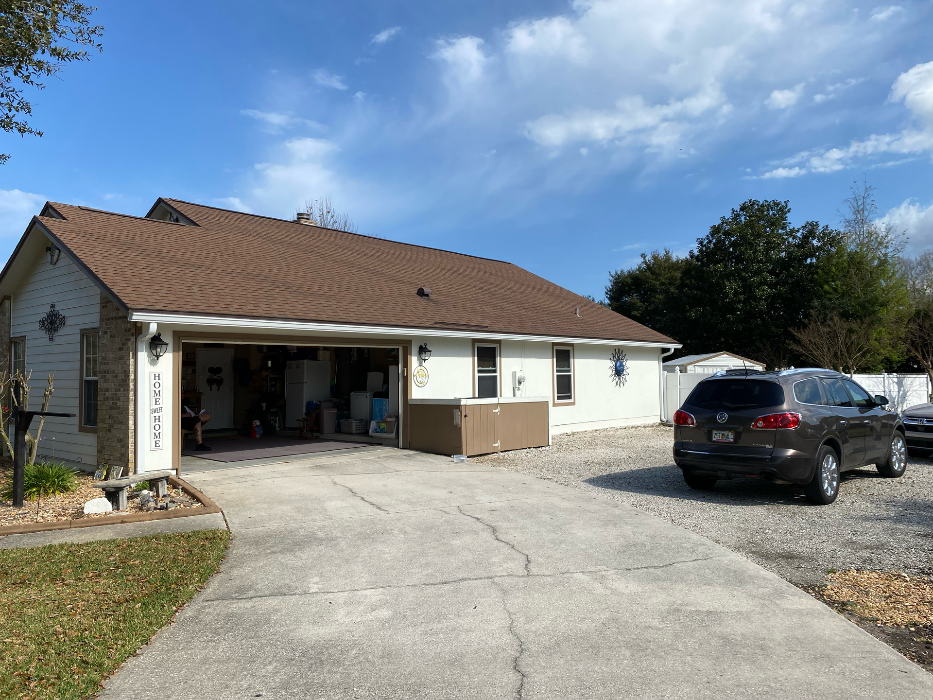 Single-story house with open garage and parked SUV on a driveway under a blue sky