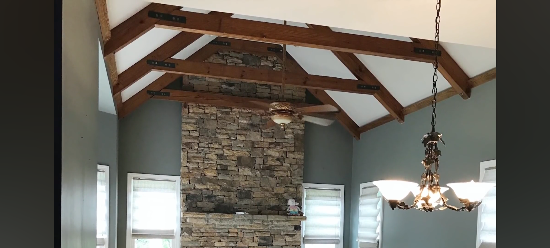 Interior with stone fireplace, wood beams, and chandelier. 