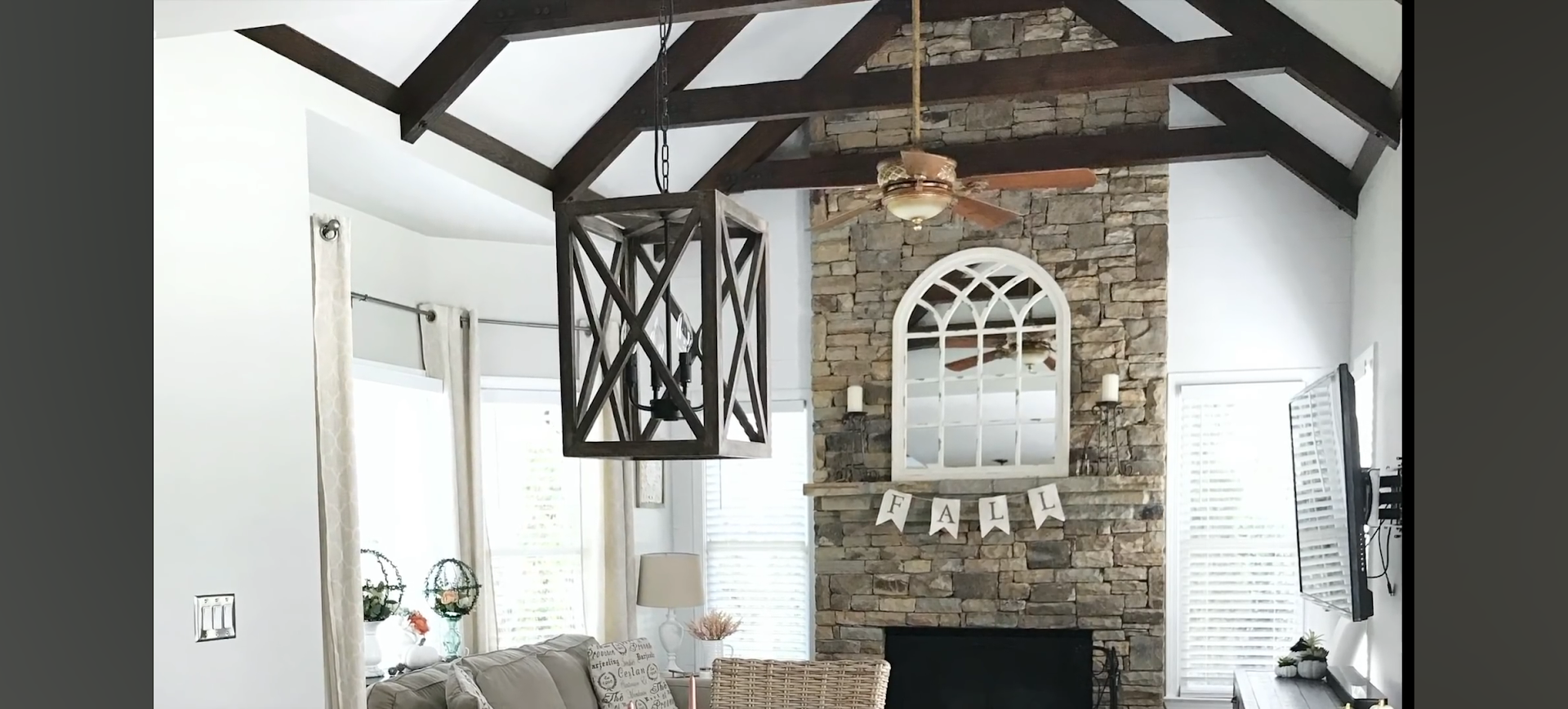 Living room with a stone fireplace, exposed wooden beams, and a decorative lantern.