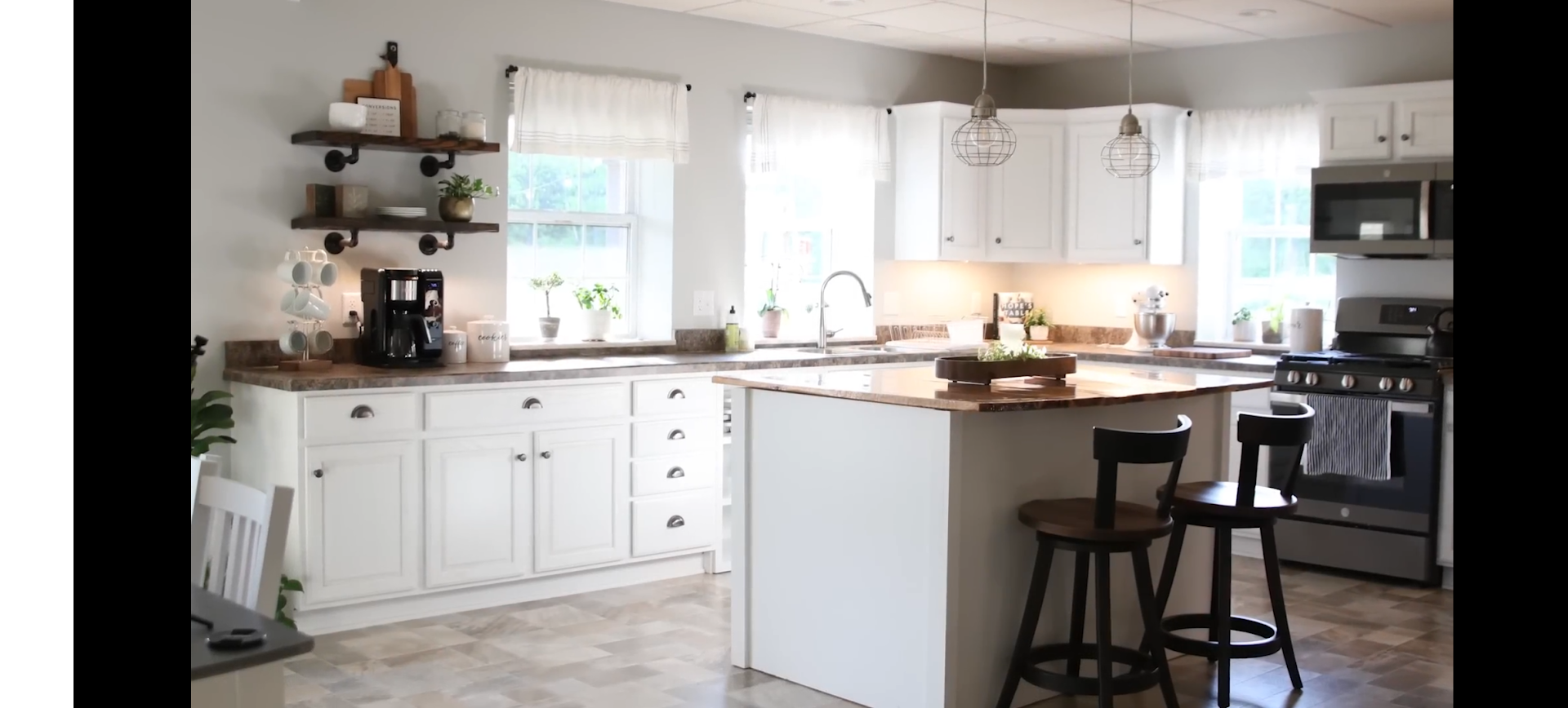 A bright, white kitchen with a kitchen island, and a stainless steel oven. 