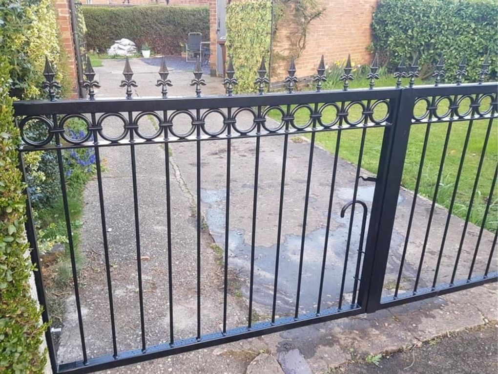 Low black double driveway gates with a band of rings and spear tops