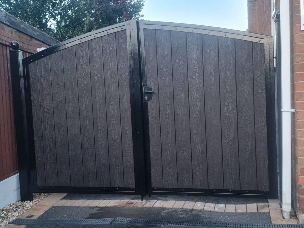 Arched pair of grey composite driveway gates in a black frame
